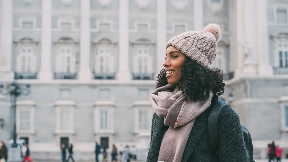 Young black woman drinking coffee wandering in the streets of Madrid on winter tourist